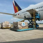 Proses bongkar muat kargo ke dalam pesawat komersial di bandara, menggambarkan layanan pengiriman cargo udara